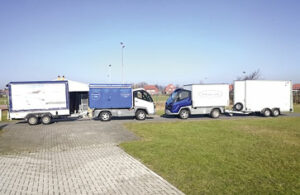 Zwei Elektrofahrzeuge warten vor der Verteilhalle am Flughafen auf neue Pakete und Päckchen zur Auslieferung. Foto: Robin Kuper